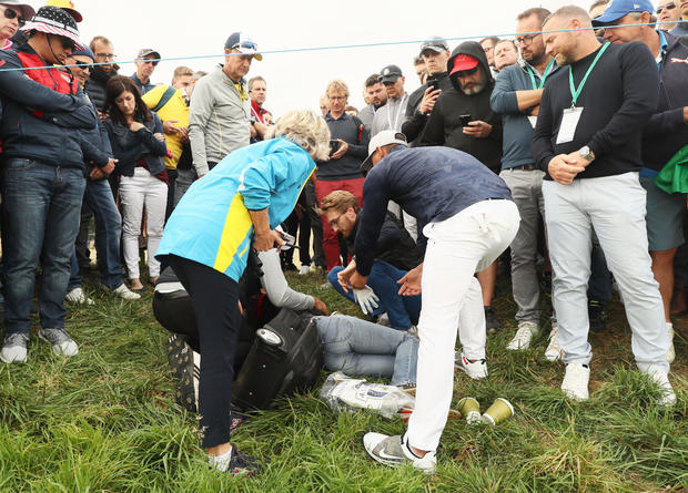 Brooks Koepka of the United States signs a glove and gives it to a woman who was hit by his ball on the sixth hole during the Ryder Cup at Le Golf National on Sept. 28, 2018, in Paris, France. 