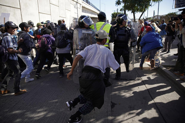 Migrants break past a line of police as they run toward the Chaparral border crossing in Tijuana, Mexico, Nov. 25, 2018, near the San Ysidro entry point into the U.S. 