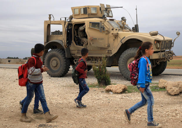 FILE PHOTO: Syrian schoolchildren walk as U.S. troops patrol near Turkish border in Hasakah 