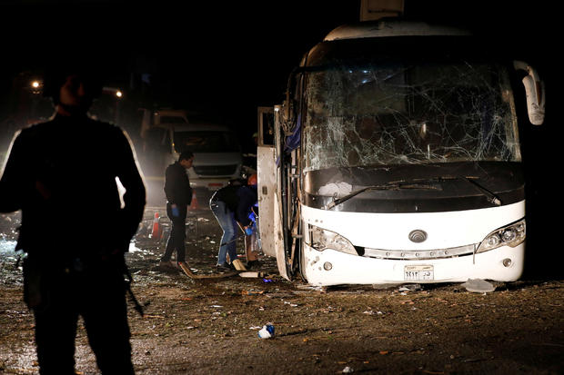 Police officers inspect a scene of a bus blast in Giza 