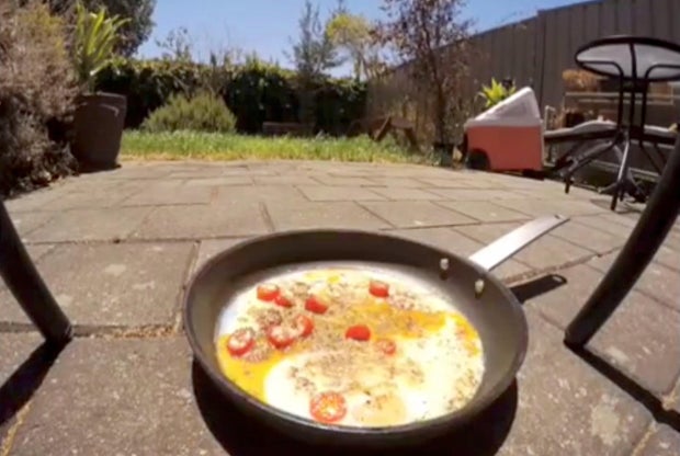 A pan with frying eggs is seen on a pavement during a heatwave in Adelaide