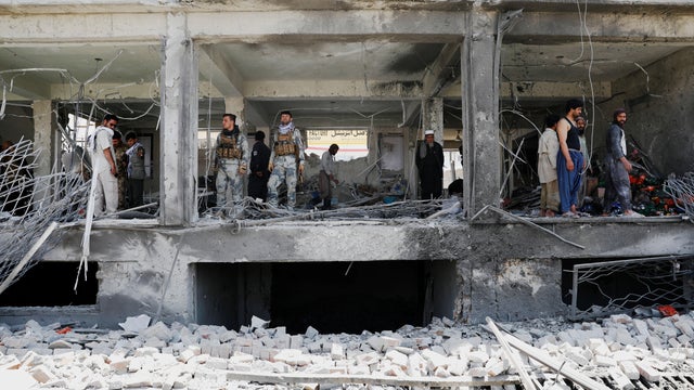 Afghan security forces inspect a damaged building at the site of a blast in Kabul, Afghanistan