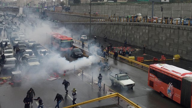 Riot police tries to disperse people as they protest on a highway against increased gas price in Tehran