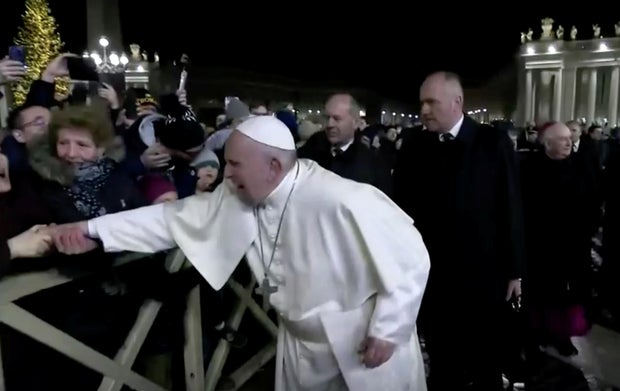 A woman grabs Pope Francis' hand and yanks him toward her at St. Peter's Square at the Vatican in this still image taken from a video December 31, 2019. 