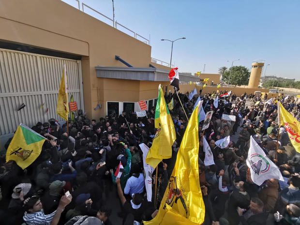 Protesters and militia fighters gather to condemn air strikes on bases belonging to Hashd al-Shaabi, outside the main gate of the U.S. Embassy in Baghdad 