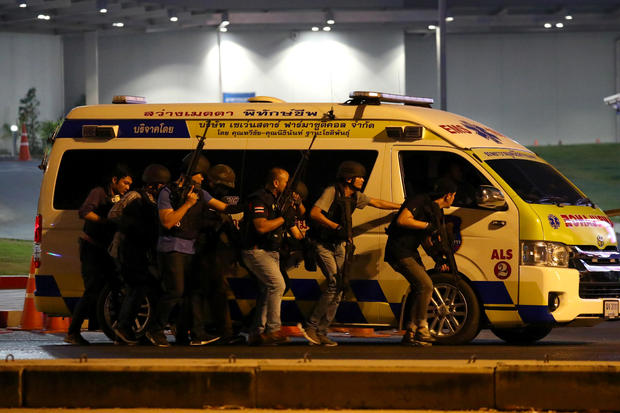 Thailand security forces take cover behind an ambulance as they chase a shooter hidden in a shopping mall after a mass shooting in front of the Terminal 21, in Nakhon Ratchasima, Thailand 