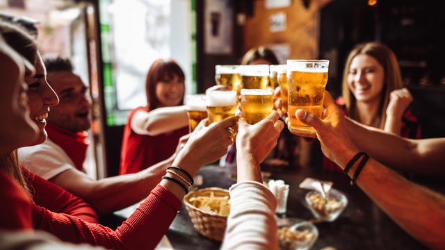 people talking and toasting in a pub with the beers