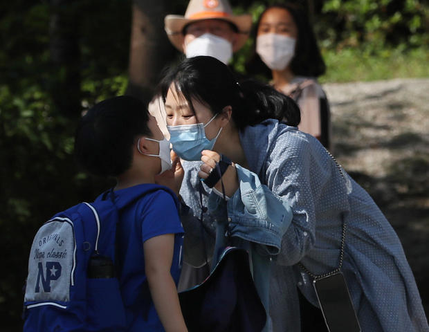 A mother kisses her child as they both wear masks to avoid the spread of the coronavirus disease (COVID-19) at an elementary school in Seoul 