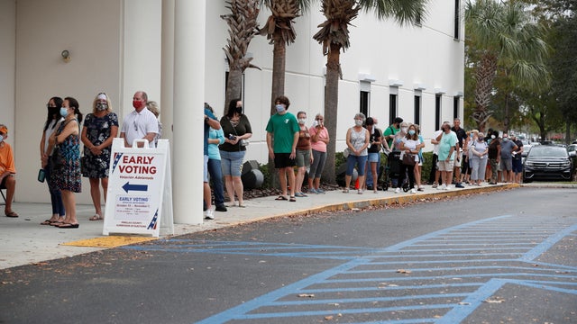 People line up at a polling station as early voting begins in Florida