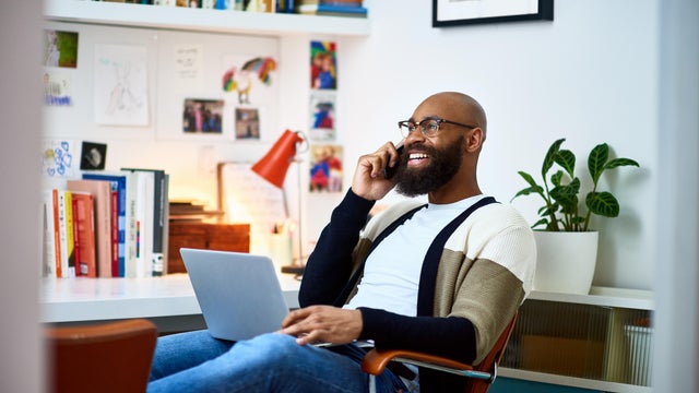 Cheerful businessman working from home on phone