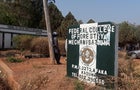 Man rests on a pole beside the signage of the Federal College of Forestry Mechanization where gunmen abducted students, in Kaduna 