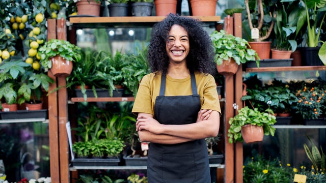 Portrait of cheerful owner standing at market stall 