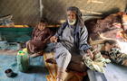 Ali al-Nehmi, 70, sits with his grandchildren in their hut at a camp for internally displaced people (IDPs) in Marib 
