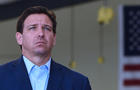 Florida Governor, Ron DeSantis listens to another speaker at 