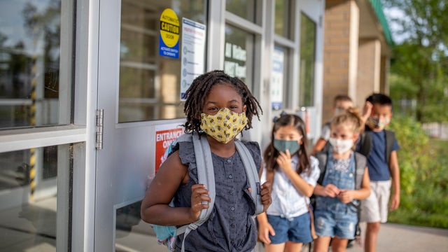 Diverse group of elementary school kids go back to school wearing masks 