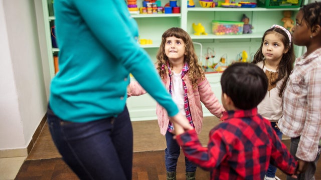 Children and teacher playing together in classroom 