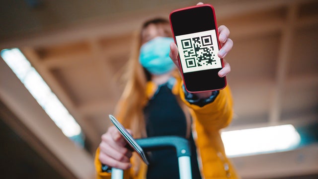 woman using mobile phone application with covid-19 test results in airport. safe travel new normal. copy space