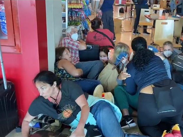 People take cover during an incident at Cancun's international airport in Mexico, March 28, 2022, in this screen capture from video.