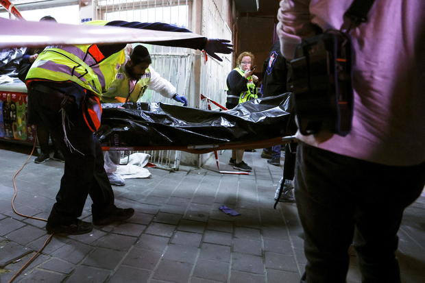 Israeli medical personnel and rescue workers evacuate a body from the scene of a fatal shooting attack on a street near Tel Aviv 