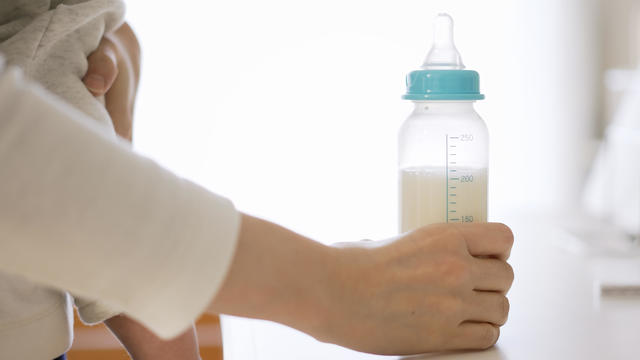 Asian female giving milk to her baby 