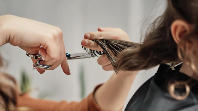 Human hands hair cut using a scissors lock of hair 